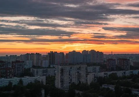 Dramatic orange and pink clouds illuminate a vast urban skyline at sunset Foto stock