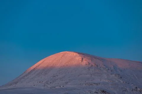 Dramatic orange and pink sunset clouds spread across a blue Arctic sky in A.. Stock Photos