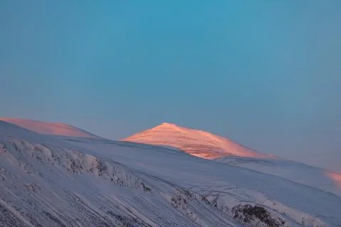Dramatic orange and pink sunset clouds spread across a blue Arctic sky in A.. Stock Photos