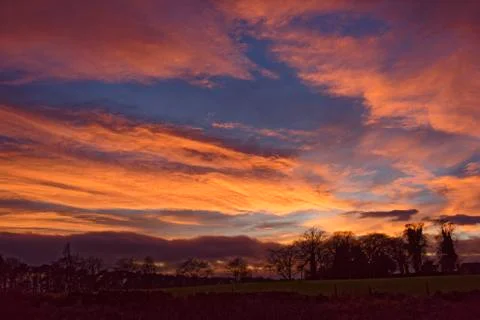 Dramatic Orange and red Clouds lit up by the setting Winter sun. Stock Photos