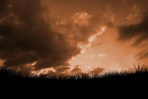 Dramatic orange cloud bank is spreading above grassy horizon silhouette in flat Stock Photos