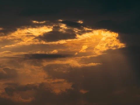 Dramatic orange golden sunset sky with dark storm clouds and glowing light .. Stock Photos