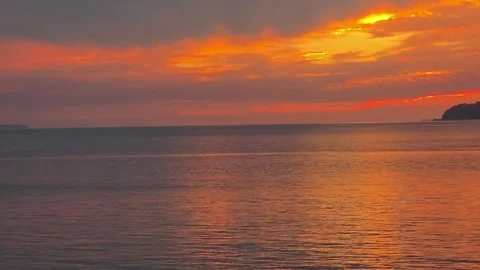 Dramatic Orange Red Sunset Clouds Reflecting on Calm Sea Stock Footage 345387640
