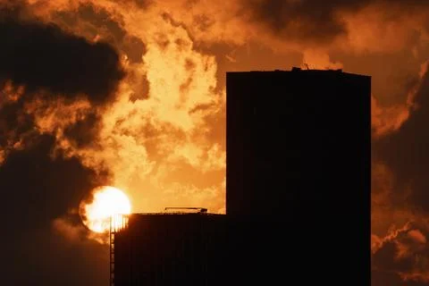 Dramatic Orange Sunset Behind Dark Urban Building Silhouette, Sun Disk Stock-Fotos