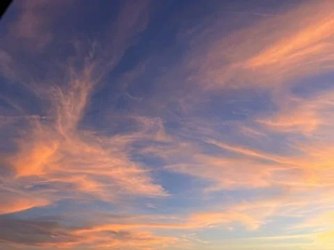 Dramatic orange sunset sky with cirrus clouds and airplane contrails Stock Photos