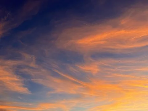 Dramatic orange sunset sky with cirrus clouds and airplane contrails Stock-Fotos