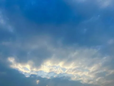Dramatic Overcast Sky with Soft Golden Sunlight Breaking Through the Dark Clouds Stock-Fotos