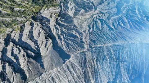 Dramatic overview of eroded ash flows and green oases snaking through Bromo Foto stock