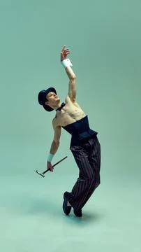 Dramatic performer curving body backward, elevating cane towards unseen heights Stock Photos