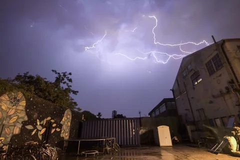 Dramatic photo of a lightning storm over graffiti and warehouses Stock Photos