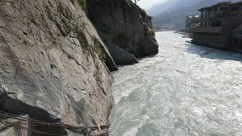 Dramatic photo: rushing river between steep rocky cliffs and buildings. Stock Photos