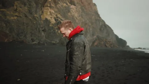 Dramatic picture of blonde attractive man on famous Reynisfjara beach, Iceland Stock Footage 254395058
