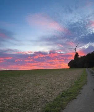 Dramatic pink and orange sunset clouds illuminate a blue evening sky above a Stock Photos