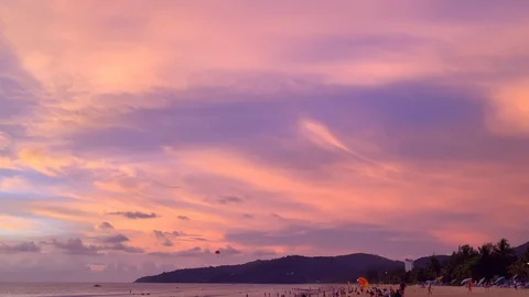 Dramatic pink cloudscape sunset. Evening on crowded beach with tourists Vídeo Stock 129074401
