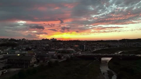 Dramatic pink sunset over rush hour traffic in small town by river 스톡 동영상 219221430