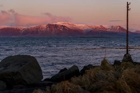 Dramatic Pink Sunset Over Snow-Capped Mountains and Ocean Stock Photos