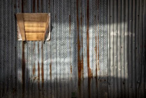 A dramatic play of light and shadow transforms a rustic corrugated metal su.. Stock Photos