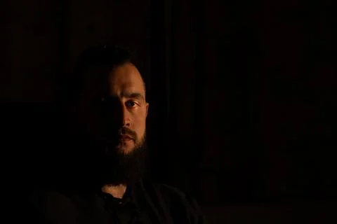 Dramatic portrait of a bearded man with intense gaze in low light Stock Photos