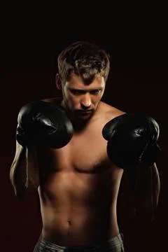 This is a dramatic portrait of a boxer in old boxing gloves on a dark background Stock Photos