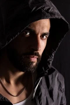 Dramatic portrait of handsome bearded man wearing dark hood with low light on Foto stock