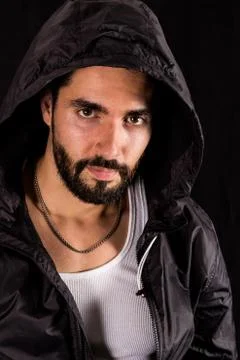 Dramatic portrait of handsome bearded man wearing dark hood looking at camera Stock Photos