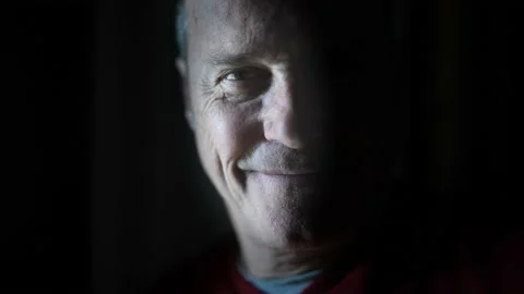 Dramatic portrait of a mature man in a low light smiling. Stock Footage 148110256