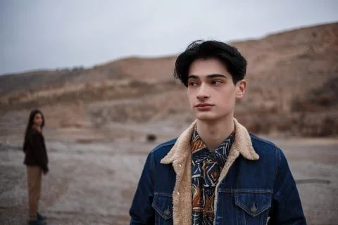 Dramatic portrait of a young brunette guy in cloudy weather. somewhere behind Stock Photos
