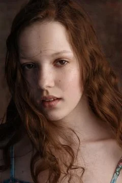Dramatic portrait of a young cute redhead teenage girl with curly haircut in  Stock Photos