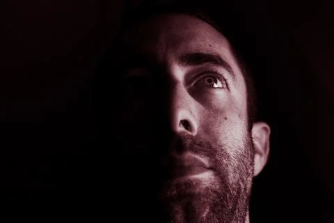 Dramatic portrait of a young man half expressionless face in deep shadow look Stock Photos