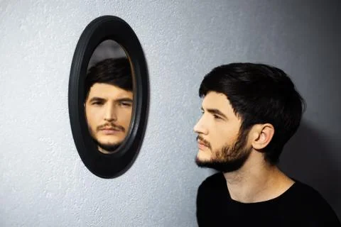 Dramatic portrait of young thoughtful guy, looking at his reflection in mirror. Stock Photos