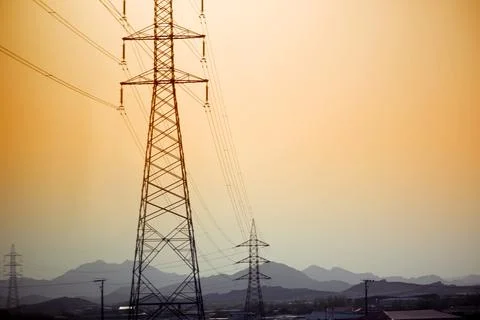 Dramatic power lines against warm gradient sky for infrastructure projects Stock Photos