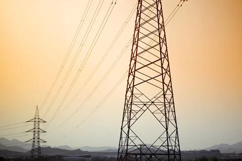 Dramatic power lines against warm gradient sky for infrastructure projects Stock Photos