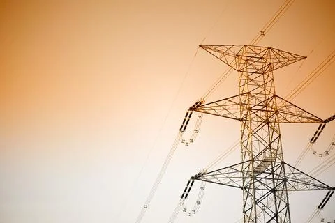 Dramatic power lines against warm gradient sky for infrastructure projects Stock Photos