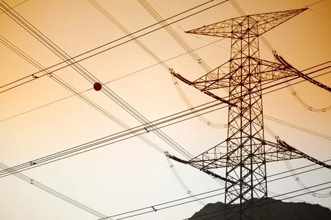 Dramatic power lines against warm gradient sky for infrastructure projects Stock Photos