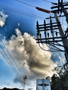 Dramatic Power Lines and Utility Pole Against Fiery Blue Sky Stock Photos
