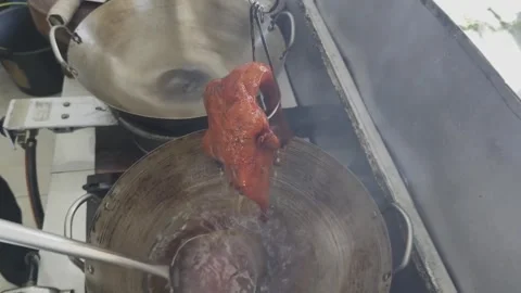 A dramatic process of dousing Peking duck in scalding hot oil from a wok. Stock Footage 297341194