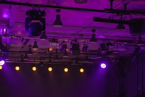 Dramatic purple stage lighting illuminates overhead rigging and spotlights Stock Photos
