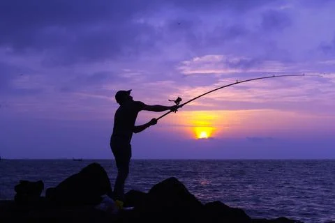 Dramatic Purple Sunset Behind an Arched Fisherman Silhouette 0041 Stock Photos
