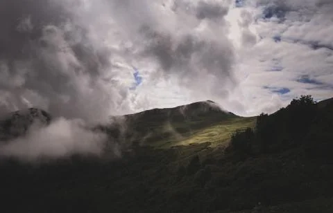 Dramatic Rain Clouds Over a Huge Mountain, Sun Piercing Through, 5K Stock Photos