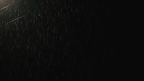 A dramatic of rain falling against a dark background, illuminated by a light 스톡 동영상 312168964