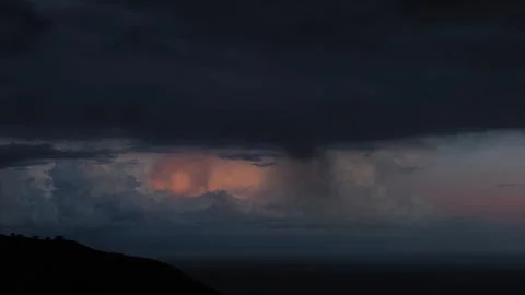 Dramatic rain shaft beneath dark storm clouds over Mediterranean sea Stock Photos