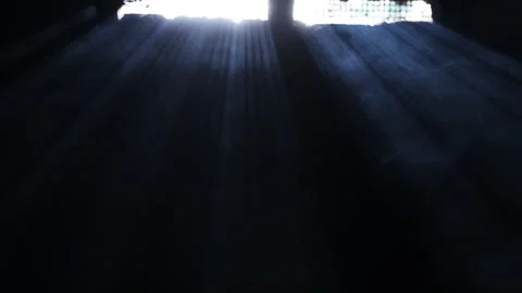 Dramatic rays of sunlight stream through an opening into a dark interior. 库存影片 292198692