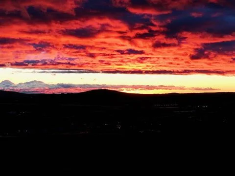 Dramatic Red and Orange Sunset Over Silhouetted Landscape Stock Photos