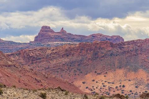 Dramatic red cliffs rise against a cloudy sky. Stock Photos
