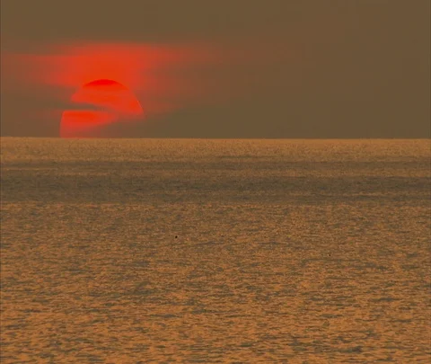 Dramatic red hot sun setting over golden ocean waves Stock Footage 86747534