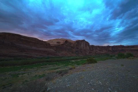 Dramatic red rock canyon at dusk with streaky storm clouds Stock Photos