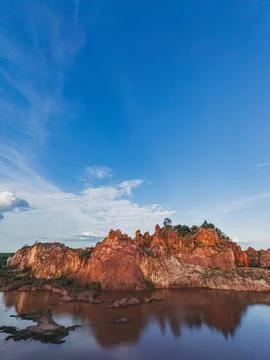 Dramatic Red Rock Formations Reflected in Calm Water Under a Clear Blue Sky.. Stock Photos