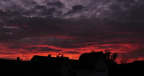 Dramatic red sky over the village roofs. Beautiful late autumn red sunset, 4k Stock Footage 142815916
