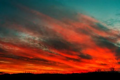 Dramatic red sky with stretched gray clouds at early morning Stock Photos