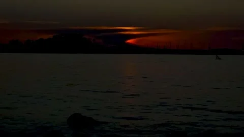 Dramatic red sun setting behind mountain silhouette over calm sea in Denia h 스톡 동영상 337957884